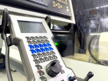 Bir CNC makine kontrol paneli atölyede aktif bir üretim süreci sırasında sayısal değerleri ve düğmeleri gösterir. Çevre modern ve işlevseldir..