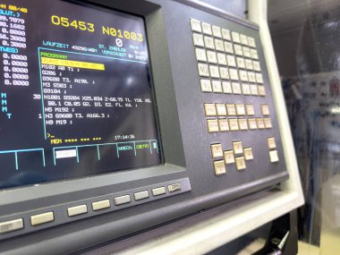 CNC kontrol paneli, akşam saatlerinde bir üretim tesisinin yüksek teknoloji ortamını yansıtan detaylı programlama verilerini gösterir..