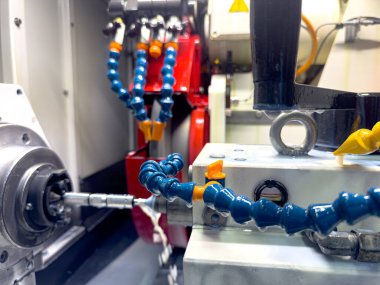 Hassas bir atölyedeki sofistike makinelerin detaylı bir görüntüsü. Robot kollar ve karmaşık bileşenler yüksek teknoloji üretimi için birlikte çalışırlar. Araçlar en uygun performans için konumlandırılmıştır.