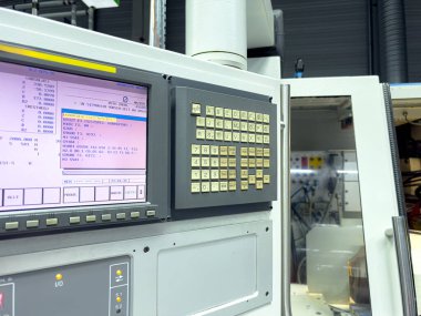 Bir imalat tesisinde gelişmiş bir kontrol panelinin yakın görüntüsü. Çeşitli veri okumaları ve sayısal tuş takımı görülebiliyor, bu da cihazların izlendiğini gösteriyor.