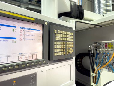 Bir fabrika ortamında gelişmiş bir üretim sürecini temsil eden dijital ekran ve sayısız düğmeye sahip bir kontrol paneli vurgulandı.