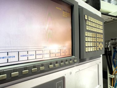 Üretim tesisinde düğmeler ve dijital ekran bulunan bir kontrol panelinin yakından görüntüsü. Panel, operatörler tarafından makine fonksiyonlarını etkin bir şekilde yönetmek için kullanılır.