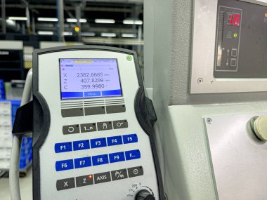 Bir CNC makinesinin kontrol paneli modern bir üretim tesisinde makine işlemleri sırasında kesin koordinatları ve ayarları gösterir. Çevre parlak ve düzenli..