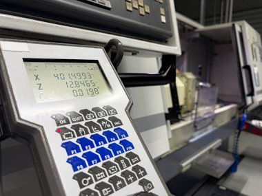 Dijital okuma aktif bir makine atölyesinde X ve Z koordinatlarının kesin ölçümlerini gösteriyor. Makineler etkin bir şekilde çalışır ve endüstriyel süreçleri iş başında vurgular..