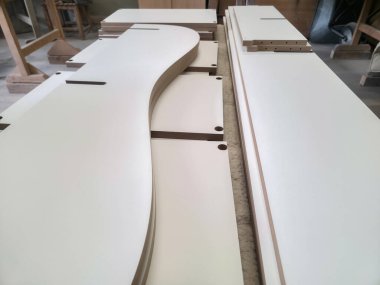 Bir marangozhanedeki tezgahta düzenlenmiş odun parçaları, enstrüman montajı için hazırlıklar. Doğal ışık boşluğu dolduruyor, işçiliği arttırıyor..