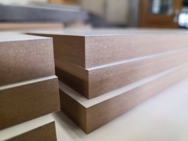 İyi aydınlatılmış bir atölyede çeşitli ahşap tahtalar var. Pürüzsüz kenarları ve temiz yüzeyleri kaliteli işçiliği ve detaylara olan dikkati yansıtıyor. Doğal renkler maddeyi vurgular.