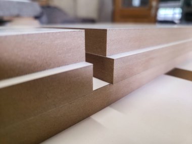 Bir ahşap atölyesinde, çeşitli kenarlar ve profiller sergilenen pürüzsüz kesilmiş ahşap paneller gösterilir..