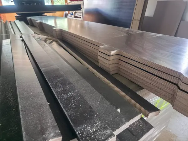 Yığınlanmış ahşap kalaslar parlak bir atölyede güzelce düzenlenir. Doğal ışık, mobilyaya veya kabineye dönüşmeyi bekleyen parlak yüzeylerine vurgu yapıyor..