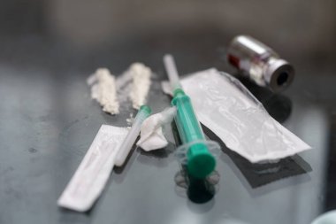 Bir şırınga yansıtıcı yüzeyde, bir şişe, filtre ve ampulün yanında yatar. Ayarlar steril odaklı acil tıbbi hazırlık öneriyor..