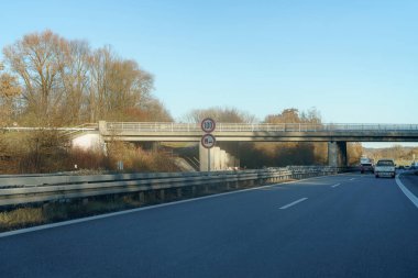 Bir yol, saatte 100 km hız sınırını belirleyen bir üst geçide paralel gider. Güneş ışıl ışıl parlıyor, ağaçlar aydınlanıyor yol kenarına serpilmiş bir sabahta.