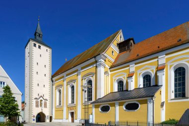 Yanı başındaki uzun çan kulesiyle çarpıcı sarı kilise, parlak mavi gökyüzüne karşı gururla duruyor. Mimari detaylarını gözler önüne seriyor ve görkemli bir yerde atmosfer yaratıyor..