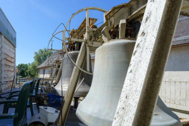 Çanlar belirgin bir şekilde eski bir yapının dışında sergileniyor, büyüklüklerini ve işçiliklerini sergiliyorlar. Parlak mavi gökyüzü, bu tarihi bölgenin huzurlu atmosferini arttırır..