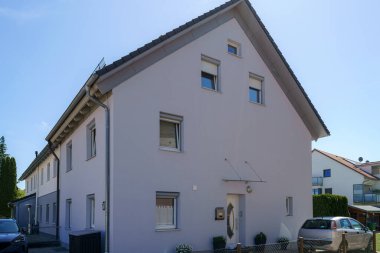 Çağdaş bir konut binasında çok sayıda penceresi olan açık renkli bir dış görünüş sergileniyor. Sessiz bir mahallede yer alan bina, modern mimari tasarımı yansıtıyor..