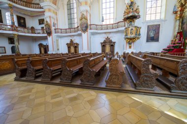 Tarihi bir kilisenin içinde karmaşık biçimde oyulmuş ahşap sıralar yer almaktadır. Zarif dekorasyonlar ve sıcak gün ışığı sakin atmosferi artırarak ziyaretçileri yansıtmaya davet ediyor..