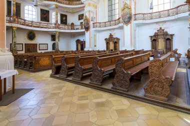 Ziyaretçiler, tarihi bir kilisenin sakin atmosferini tecrübe ediyorlar. Güzel işlenmiş ahşap sıralar ve sıcak öğleden sonra güneş ışığıyla dolu süslü dekorasyonlar..