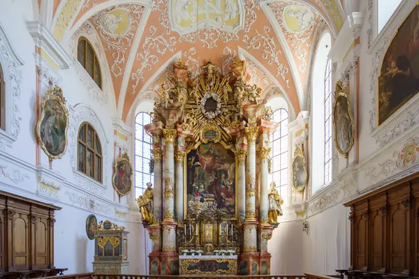 Güzel bir kilisenin içinde, göz kamaştırıcı bir barok sunağı odak noktası olarak duruyor. Karmaşık freskler ve heykeller duvarları süslüyor, büyük pencerelerden yayılan doğal ışıkla aydınlanıyor..