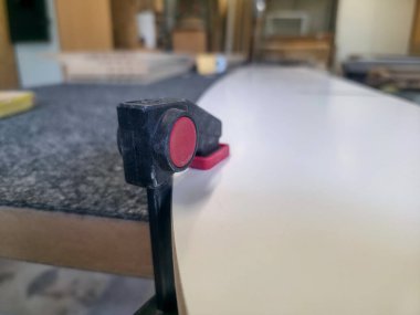 Sörf tahtası şekillendirme aracı, sörf tahtası işçiliğinde gerekli hassasiyeti vurgulayan bir atölyenin kenarında duruyor. Doğal ışık boşluğu dolduruyor, maddeleri vurguluyor.
