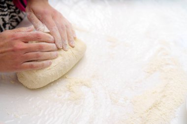 Neşeli bir mutfakta un kaplı bir yüzey üzerinde iki el çalışır. Un gün ışığında dans eder ve kişi lezzetli bir fırın hazırlar. Pişirme sürecinin tadını çıkarır..