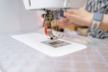 Dikiş makinesi nazikçe mırıldanırken, eller iğne altında kumaşa ustalıkla rehberlik ediyor, yaratıcı bir öğleden sonra rahat bir ev ortamında ayrıntılı tasarımlar yapıyor..