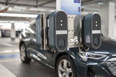 Bu kurulum, şık bir elektrikli arabanın yanına yerleştirilmiş bir çift elektrikli araç şarj istasyonu içeriyor..