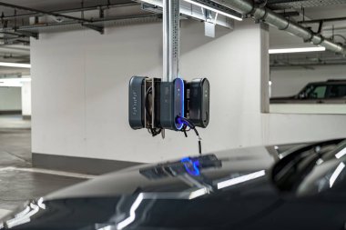 İyi ışıklandırılmış, modern bir otoparka elektrikli araç şarj istasyonu kuruldu. Ekipmanlar bir direğe monte edilerek sürücülere kolay erişim sağlanıyor..