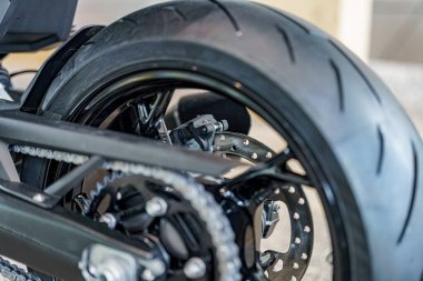 Lastik ve fren bileşenlerini içeren bir motosiklet tekerleğine detaylı bir bakış, tasarımda yer alan hassas mühendisliği vurguluyor. Etkinlikte işlevsellik ve estetik üzerinde duruluyor.