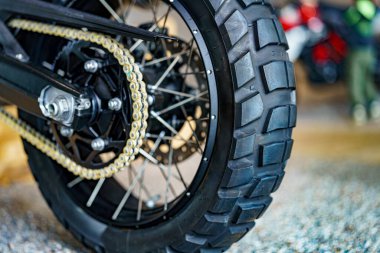 İyi ışıklandırılmış bir atölyedeki engebeli lastiğin yakın plan görüntüsü. Görüntü, dayanıklılığı vurgulayarak lastik ve çevreleyen mekaniklerin detaylarını yakalıyor..