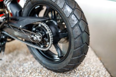 Bu yakın perspektif, çakıllı bir yüzey üzerinde dinlenen eşsiz lastik izlerine sahip bir motosiklet lastiğini vurgular, bisiklet sürmek için gerekli yapı ve kavramayı gösterir.