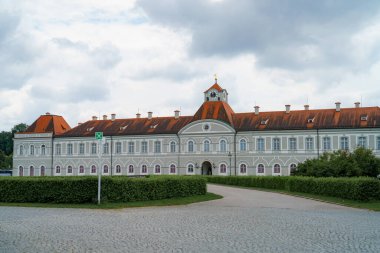 Bu tarihi yapı, seçkin saat kulesi ve canlı kırmızı çatıları olan zarif bir mimariyi sergiliyor. Çevreleyen yeşillik, bulutlu bir gökyüzü tarafından vurgulanan sakin cazibesini artırır..
