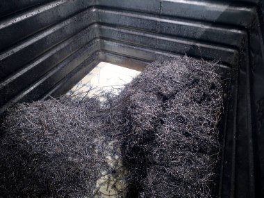 Metal talaşları, çevreyi yansıtan büyük siyah bir konteynırda birikir. Bu, bir imalat atölyesinde yapılan çalışmaların resmedildiği endüstriyel bir mekanizmanın bir parçası..