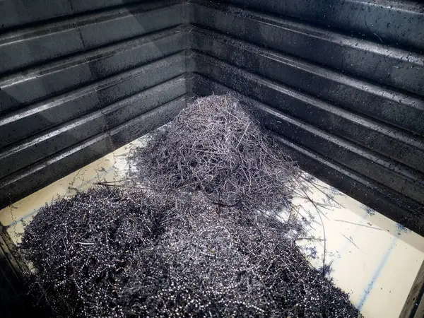 Karanlık bir konteynırda, metal talaşları makine faaliyetlerinden sonra kümelenir. Bu, üretim saatlerinde yapılan bir imalat atölyesinde sık görülen bir durumdur..