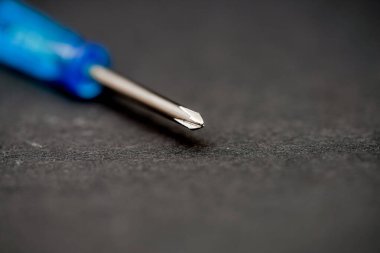 Metalik ucunu ve desenli sapını vurgulayan bir tornavidanın detaylı yakın çekimi. Alet, işçiliğini vurgulayarak karanlık bir yüzeye yerleştirilmiş..