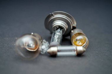 Karanlık bir yüzeye dağılmış kırık ampul ve cam parçalarından oluşan bir kolleksiyon. Farklı şekiller ve stiller cam malzemelerinin kırılganlığını vurgular.