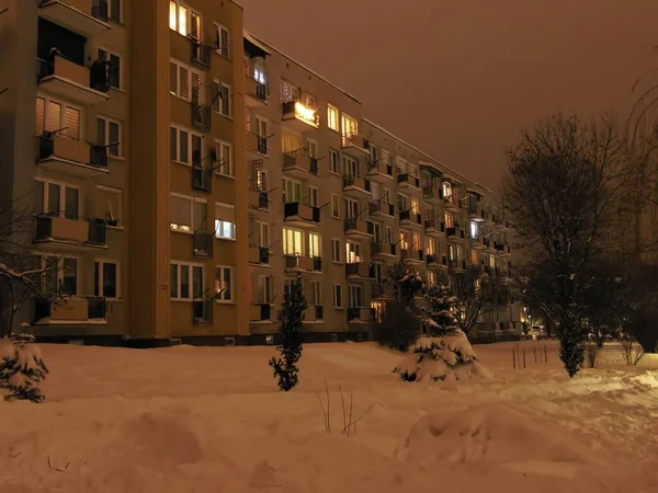 stock image A 4-storey long block of flats seen on a winter evening. You can see snow, shining windows and balconies.