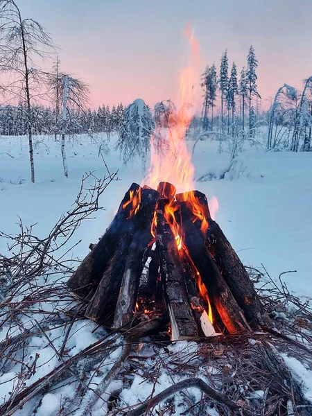 Bonfire in Swedish winter landscape at dusk.