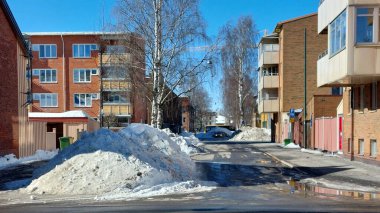 İsveç 'in kuzeyindeki Umea şehrinde kışın eriyen büyük kar yığınları küçük bir sokakta..