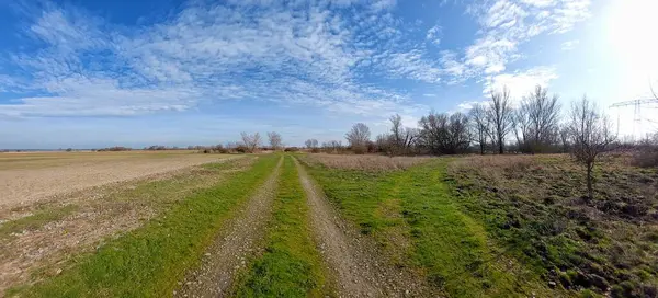 Gravel road, grass and fields in rural area in Germany.