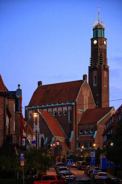 Engelbrektskyrkan Kilisesi alacakaranlıkta kırmızı tuğla cephe ve bakır elementlerle Stockholms şehrinde.
