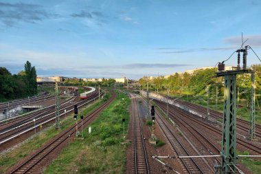 Berlin 'de birden fazla demiryolu hattı yeşil şehir manzarası boyunca açık gökyüzü altında ayrılır..
