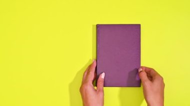Kadın Eski Mor Hardcover Kitabını Sarı arkaplanda Boş Sayfada Açar