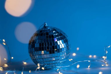 Christmas blue background with disco ball, garland and bokeh, copy space.