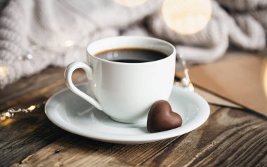 A cup of coffee and holiday sweet in the form of hearts on a wooden background, the concept of Valentines Day.