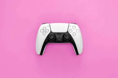 Modern white gamepad on a pink background, close up, game controller for video games, flat lay.