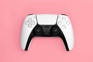 Modern white gamepad on a pink background, close up, game controller for video games, flat lay.