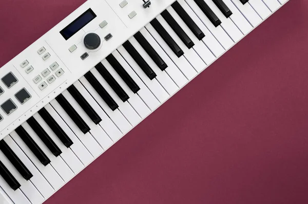 Midi keyboard on magenta background, flat lay, musical creativity concept, copy space.