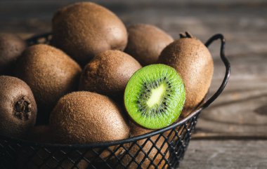 Close-up, whole kiwi and a half in a metal basket, macro shot.