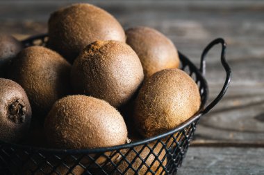 Tüm kivi meyveleriyle dolu bir hayat metal bir sepetin içinde, ahşap bir arka planda yakın plan..