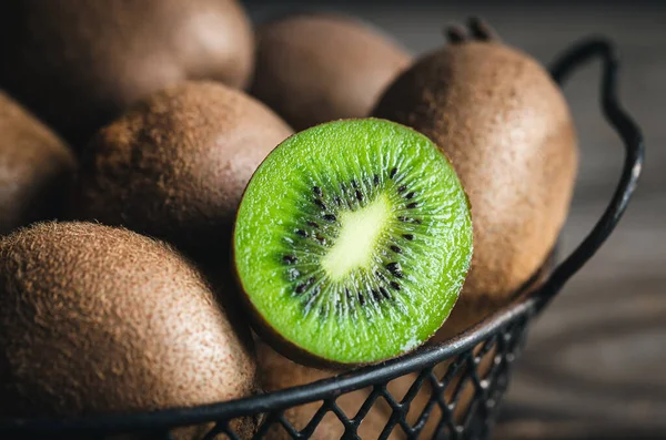 Close-up, whole kiwi and a half in a metal basket, macro shot.