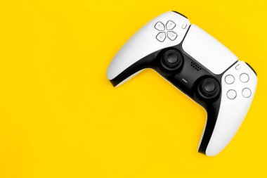 Modern white gamepad on a yellow background, game controller for video games, flat lay.