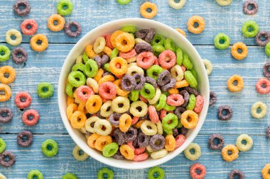Colored breakfast cereals in a bowl on a blue wooden background top view, childrens healthy breakfast, close up.